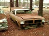 A Pontiac Tempest with a 6 cylinder engine sitting in the junk yard.